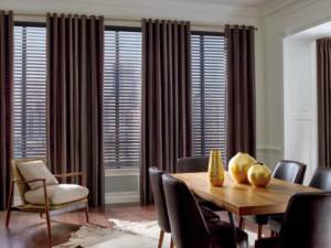 A living room with wood blinds and dark brown drapes