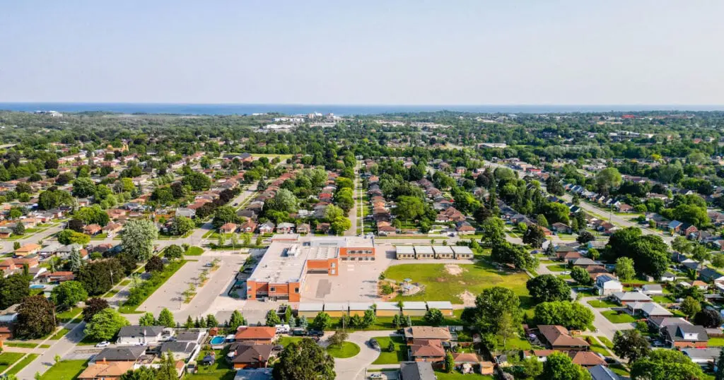 Aerial shot of Oshawa, Ontario showing residential neighborhoods, schools, and green spaces under a clear sky.