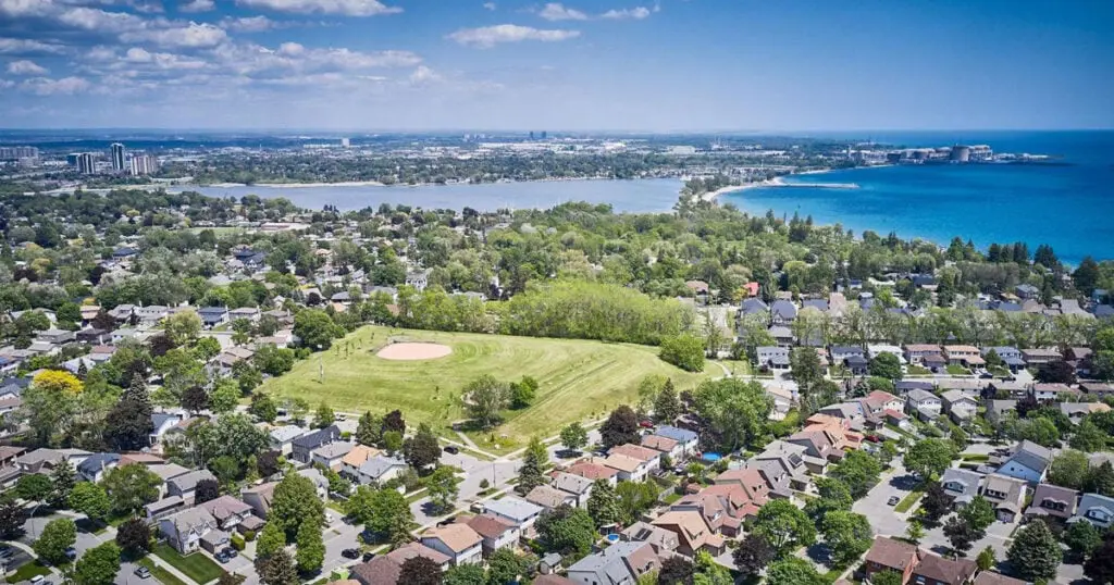Aerial view of Pickering, Ontario showing residential neighborhoods, green spaces, and Lake Ontario in the background.
