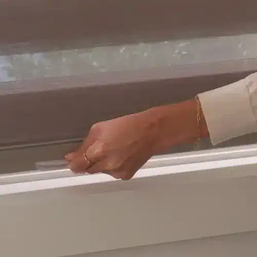 Close-up of a hand cleaning a window frame with a cloth, demonstrating home cleaning and maintenance.