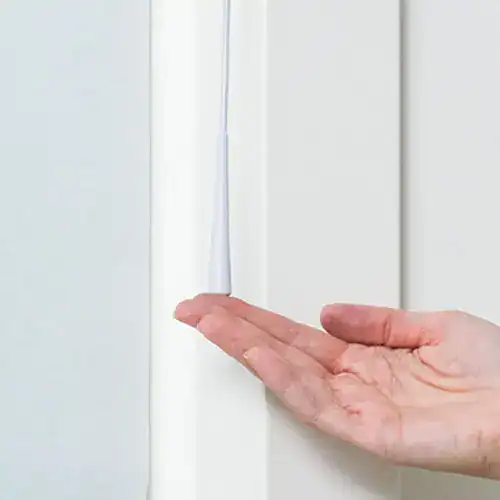 Close-up of a hand applying a sealing strip to a door frame for improved insulation and noise reduction.