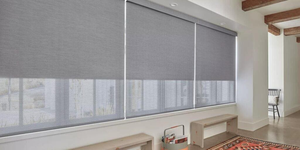 Smooth, gray roller blackout shades on large windows, providing privacy and light control in a stylish room.