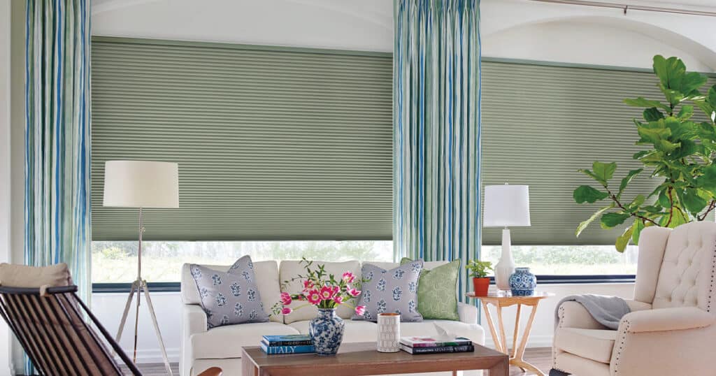 Bright, inviting interior featuring comfortable sofas, potted plants, and decorative cushions, illuminated by natural light.