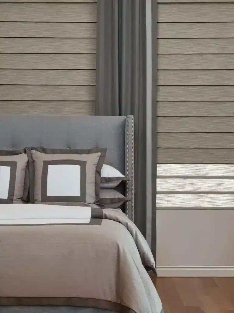 Elegant bedroom with gray upholstered headboard, decorative pillows, and stylish window treatments in a contemporary home setting.