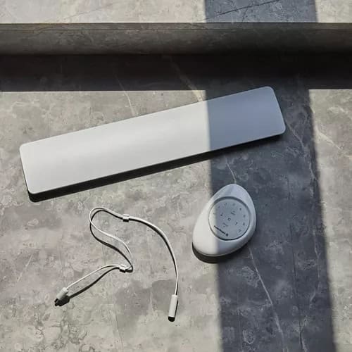 Wireless outdoor shower heater with digital control panel, mounted on gray stone tile surface for optimal outdoor shower experience.