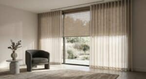 Soft beige sheer curtains and roller blinds in a modern living room with natural sunlight and a view of the garden, creating a cozy and stylish space.