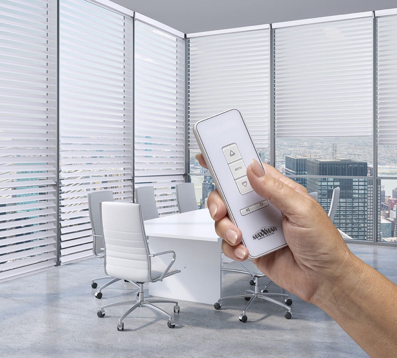 Person holding remote control in a bright, modern office with large windows and city view.