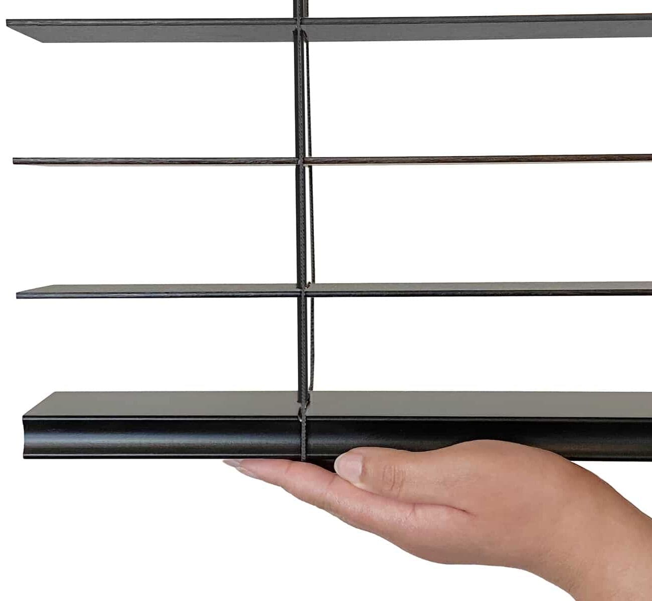 Close-up of a hand holding a cordless lift system for blinds, showing the mechanism and slats.
