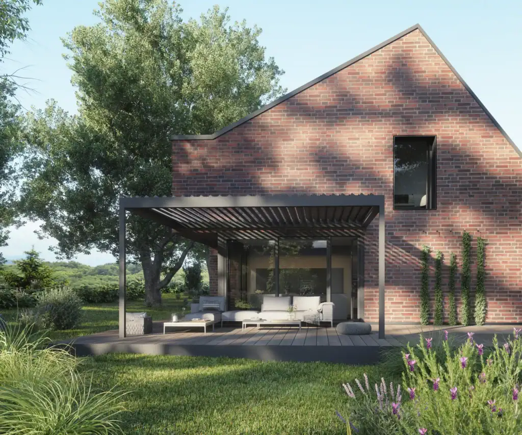 Contemporary brick house with outdoor patio, shaded seating area, lush garden, and trees in the background.
