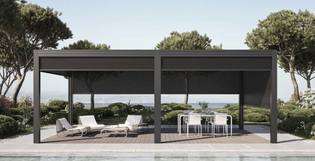 Contemporary outdoor pergola with seating and dining area, surrounded by lush greenery and trees, overlooking a scenic view.
