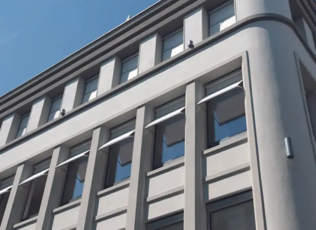 Contemporary building facade featuring large windows and vertical architectural details under a clear blue sky.